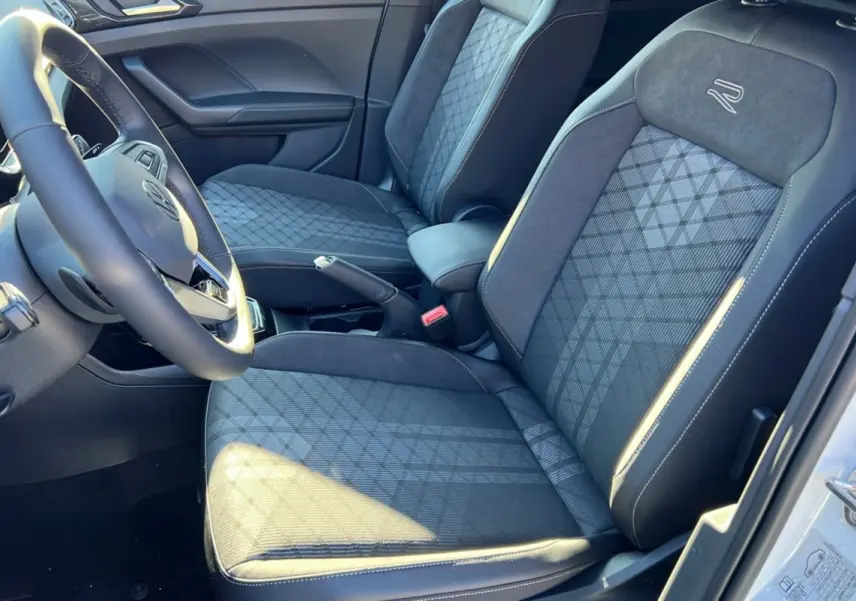 Vue intérieure côté conducteur du Volkswagen T-Cross TSI 116 DSG7 R-Line 2025, sièges tissu noir avec logo R brodé.