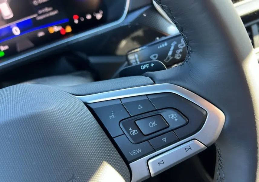 Gros plan sur les commandes multifonctions du volant cuir noir du Volkswagen T-Cross TSI 116 DSG7 R-Line 2025.