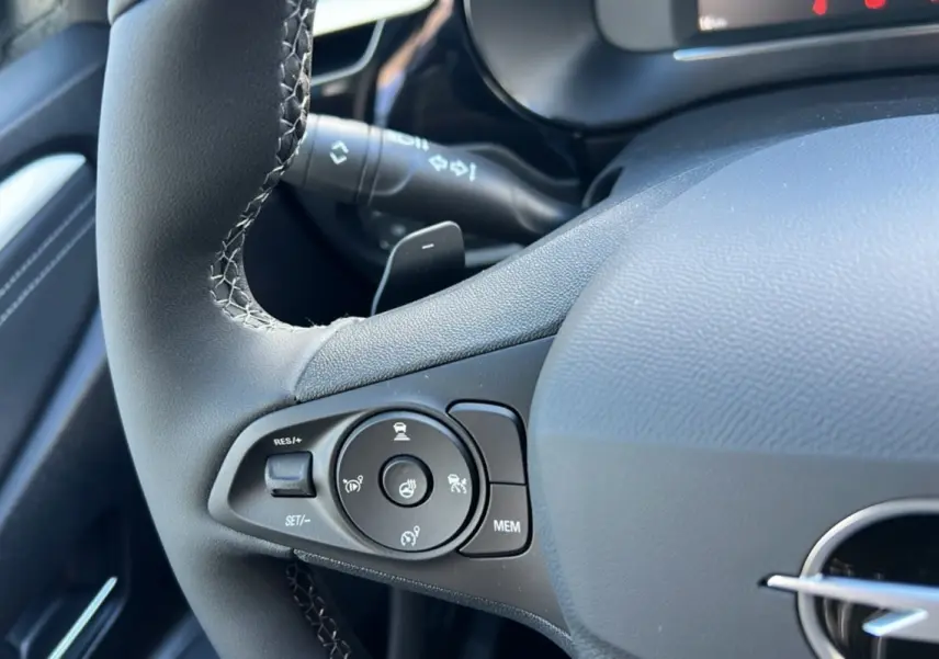 Gros plan sur le volant cuir noir de l’Opel Corsa Hybrid 2026, avec commandes multifonctions et surpiqûres visibles.