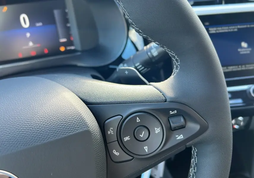 Gros plan sur les commandes multifonctions du volant cuir noir de l’Opel Corsa Hybrid 110 e-DCT6, intérieur moderne.