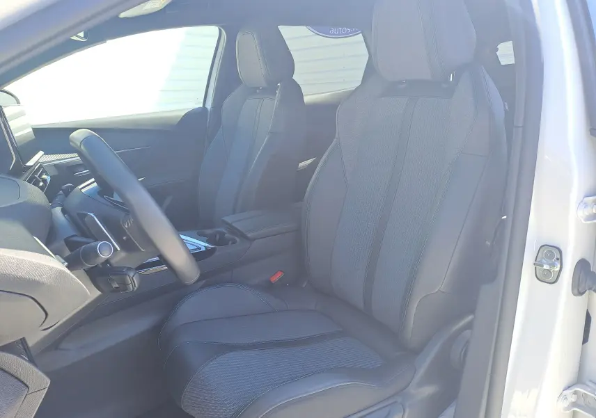 Vue intérieure côté conducteur du Peugeot 3008 2023 blanc nacré, sièges noirs en tissu et cuir avec console centrale visible.