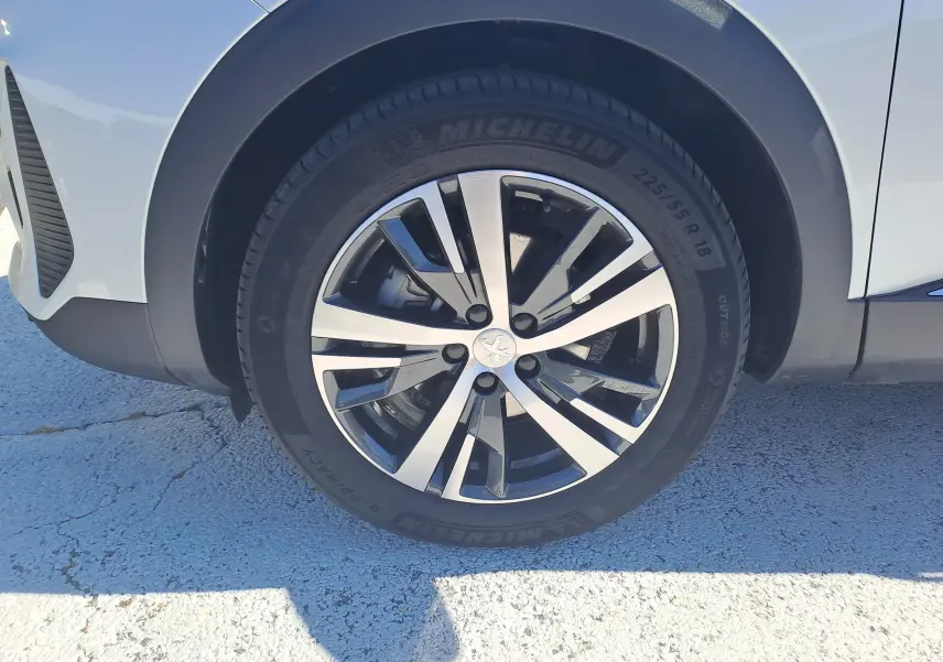 Gros plan sur la roue avant droite du Peugeot 3008 blanc nacré avec jante alliage bicolore et pneu Michelin.