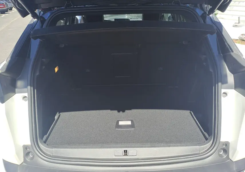 Coffre ouvert vu de l'arrière d'un Peugeot 3008 blanc nacré avec toit noir, montrant un espace de chargement vide.