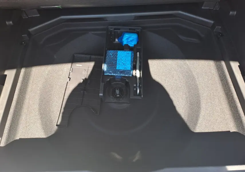 Vue plongeante sur le rangement sous le coffre du Peugeot 3008 2023, avec kit de réparation et espace vide.