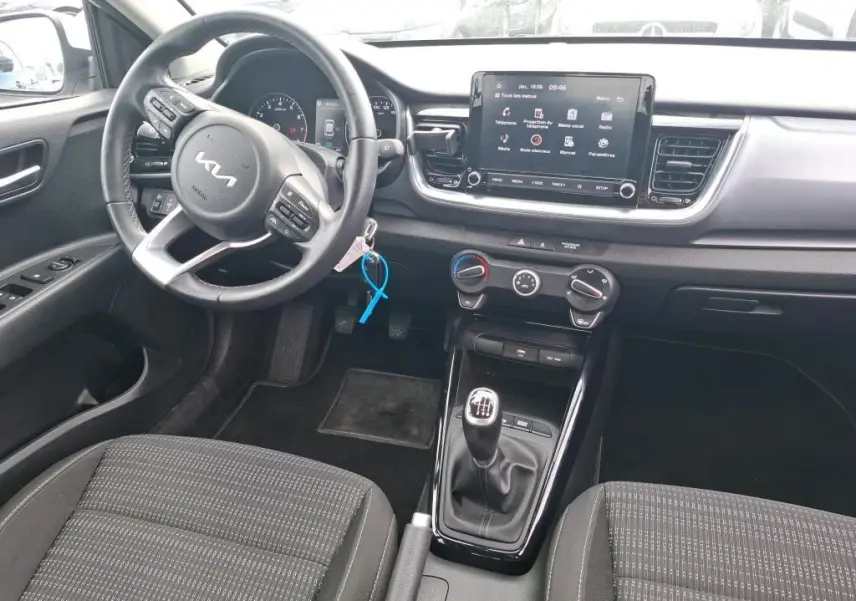 Vue intérieure côté conducteur du Kia Stonic blanc 2023, avec volant multifonction, écran tactile et boîte manuelle.