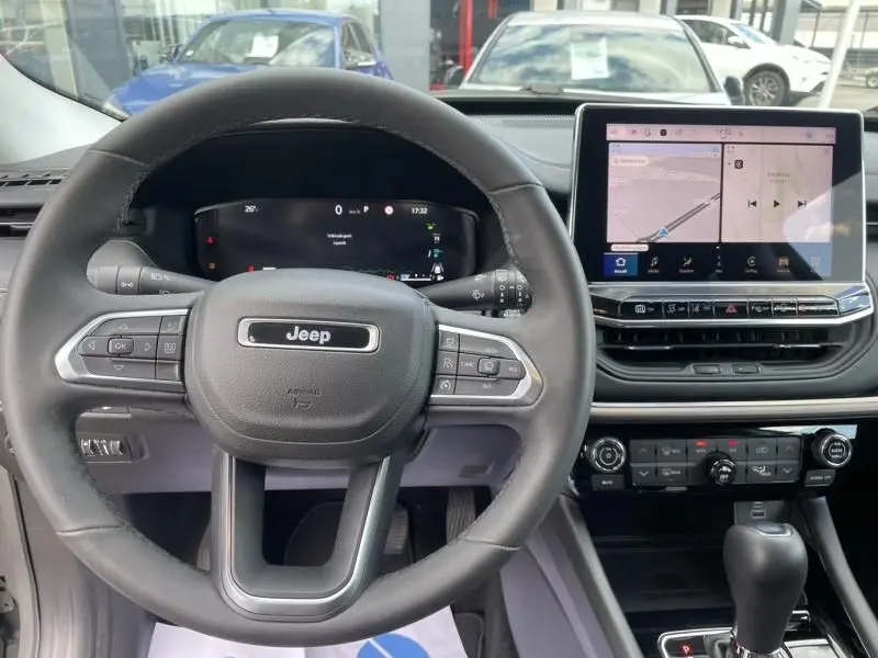Vue intérieure du tableau de bord et volant Jeep Compass gris 2023 avec écran tactile et commandes au volant.