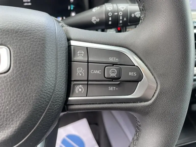 Gros plan sur les commandes de régulateur de vitesse au volant cuir noir du Jeep Compass gris hybride rechargeable 2023.