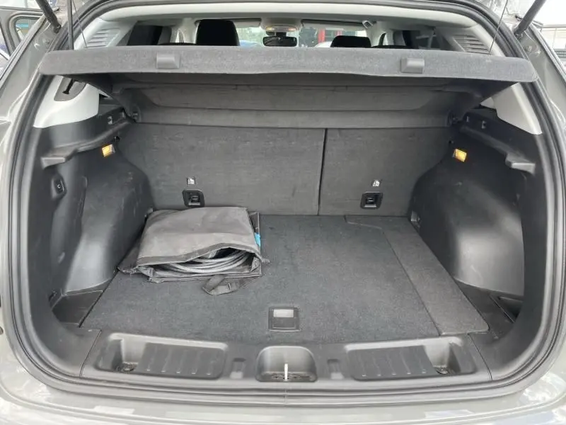 Coffre ouvert d'un Jeep Compass gris 2023 hybride rechargeable, montrant un espace de rangement avec un câble plié.