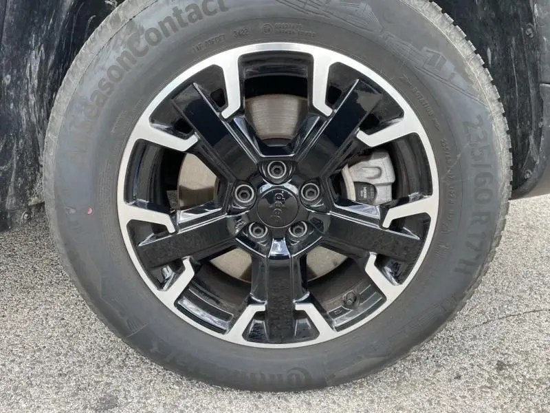 Gros plan sur la roue avant droite d'un Jeep Compass gris 2023 avec jante alliage noir et argentée distinctive.