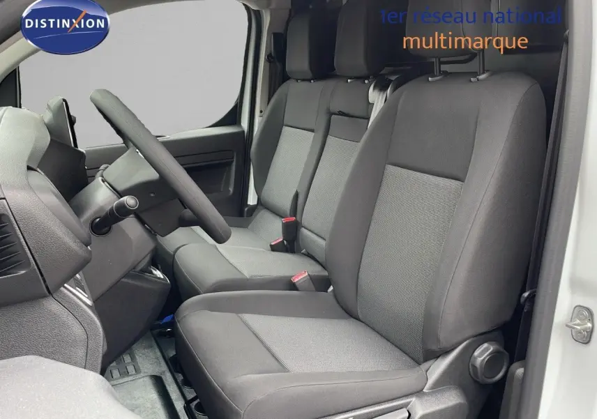 Vue intérieure côté conducteur du Peugeot Expert Fourgon blanc 2025, montrant les sièges en tissu gris et le volant.