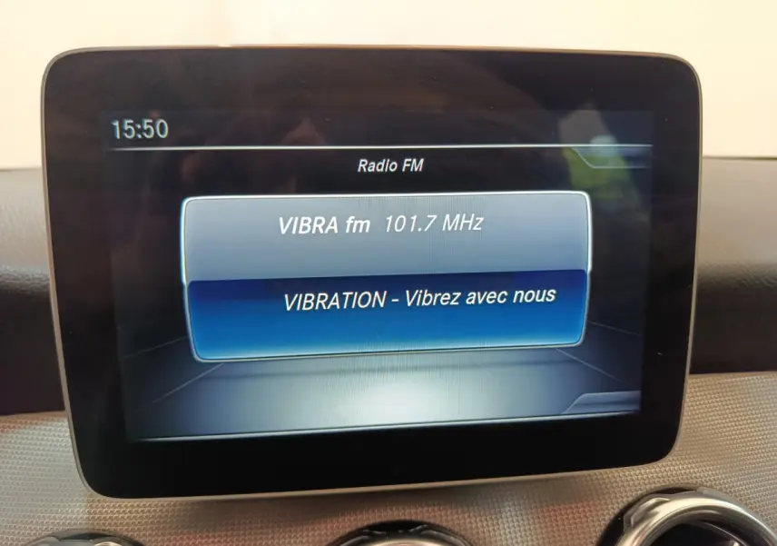Écran multimédia affichant la radio FM dans l'habitacle du Mercedes GLA 220 d Business Exec noir, vue intérieure frontale.