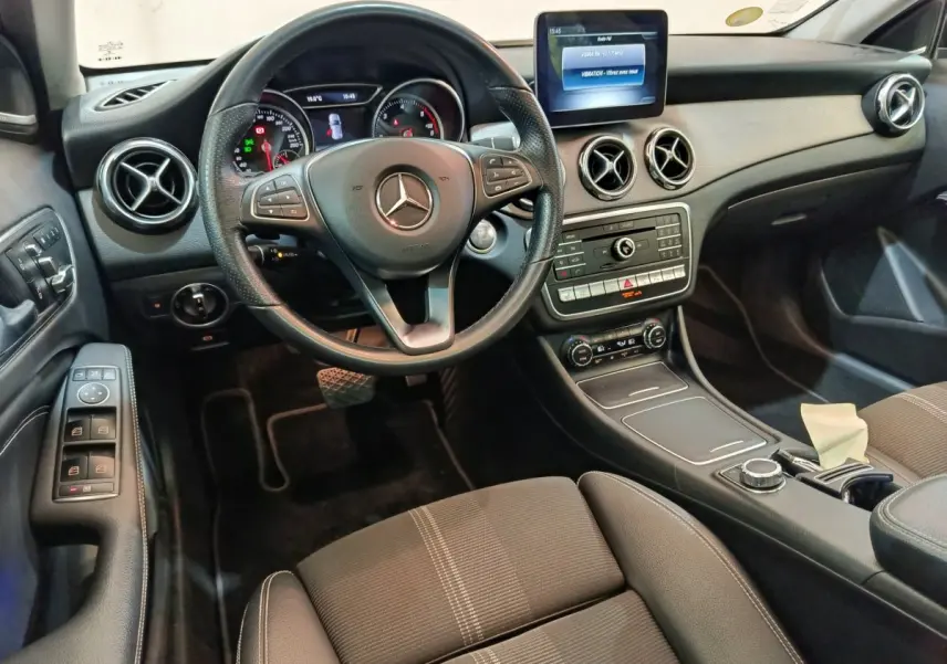 Vue intérieure côté conducteur du tableau de bord noir du Mercedes GLA 220 d avec volant cuir et écran central tactile.