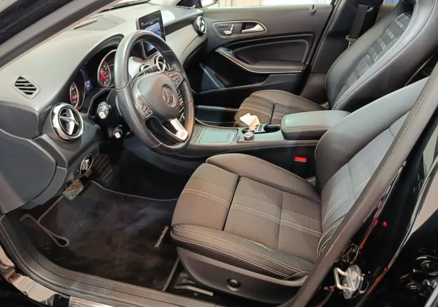Intérieur noir de la Mercedes GLA 220 d 2018 vu côté conducteur, avec tableau de bord et sièges avant en tissu et cuir.