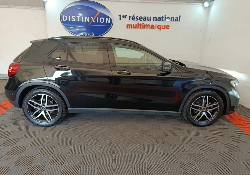 Profil côté droit d'un Mercedes GLA 220 d Business noir, avec jantes alliage et rétroviseurs électriques dans un showroom.