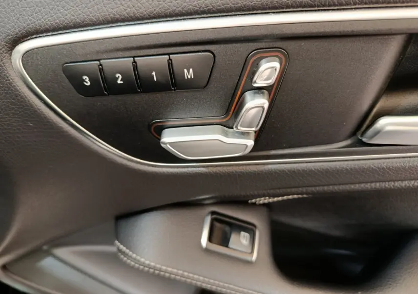Gros plan sur les commandes de réglage électrique des sièges en cuir noir à gauche dans une Mercedes GLA 220 d 2018.