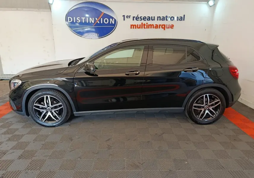 Profil côté gauche d'un Mercedes GLA 220 d noir 2018 avec jantes alliage et vitres teintées en intérieur showroom.