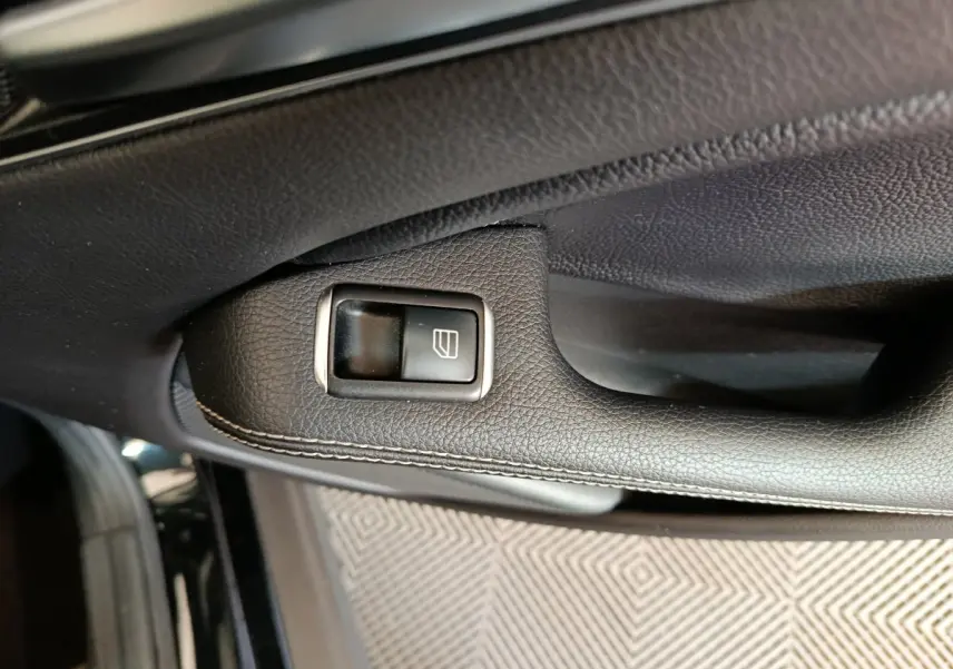 Gros plan sur la commande de lève-vitre en cuir noir sur la portière côté conducteur d’un Mercedes GLA 220 d 2018.