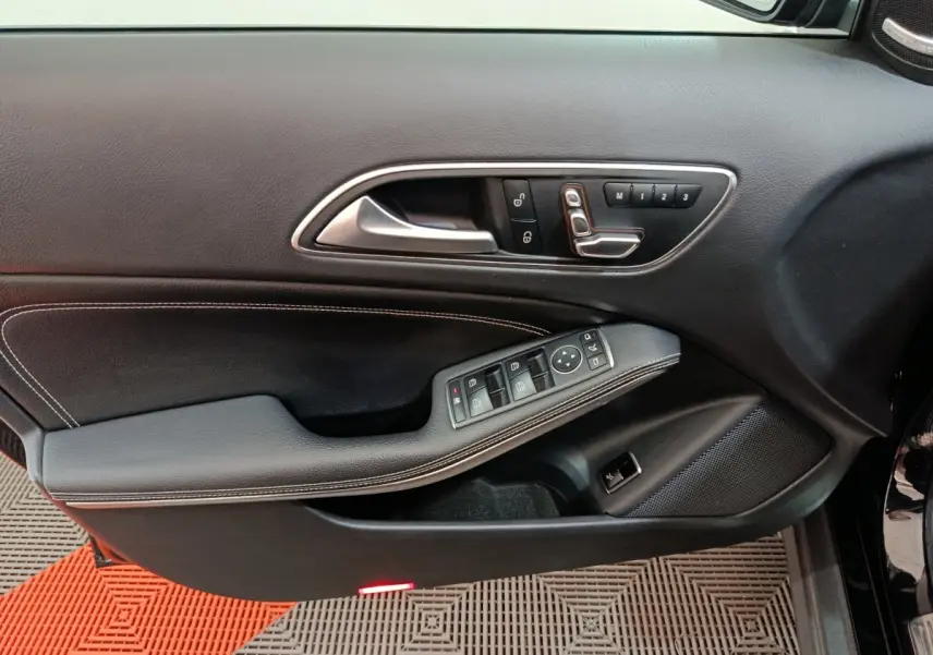 Gros plan sur la porte côté gauche noire du Mercedes GLA 220 d avec commandes de vitres et réglages siège.