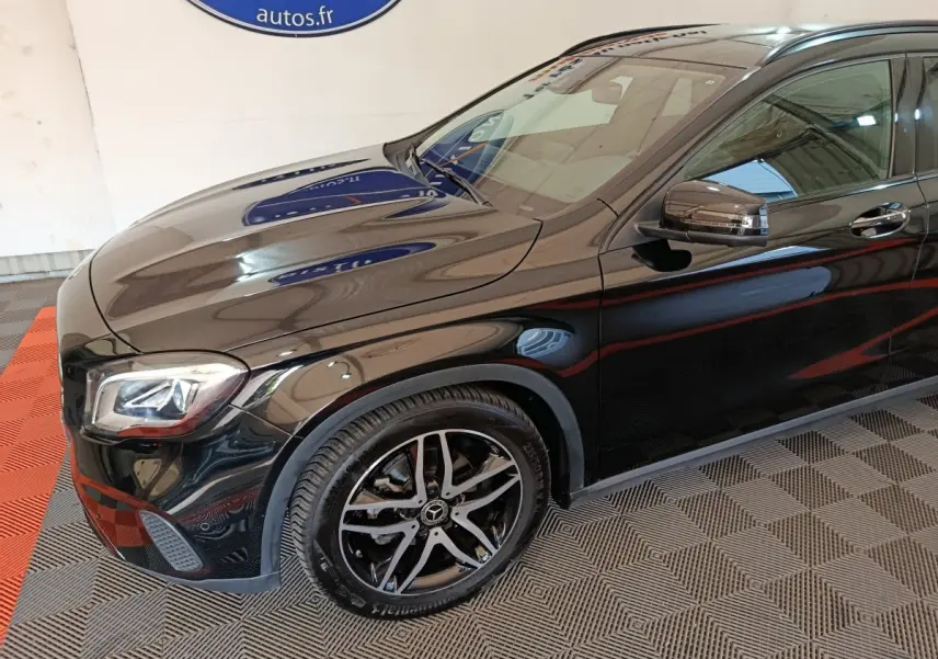 Vue 3/4 avant côté gauche d'un Mercedes GLA 220 d noir avec jantes alliage et rétroviseurs intégrant clignotants LED.