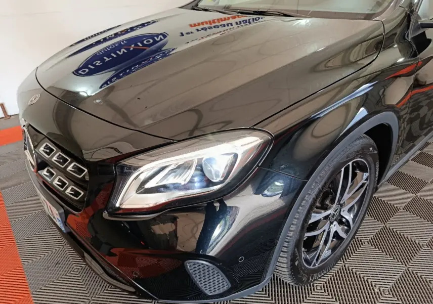 Vue 3/4 avant gauche d'une Mercedes GLA 220 d noire, phare LED allumé et jante alliage visible.