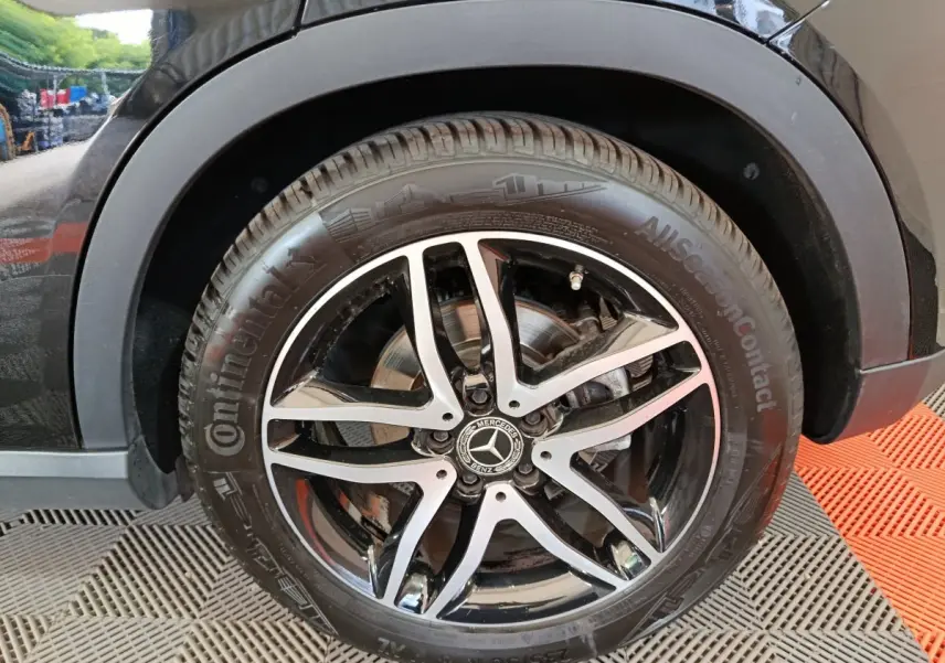 Gros plan sur la roue avant droite noire d’un Mercedes GLA 220 d avec jante alliage cinq branches bicolore.