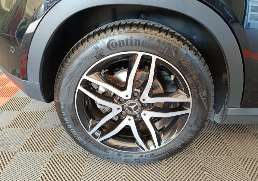 Gros plan sur la roue avant gauche noire d’un Mercedes GLA 220 d avec jante alliage cinq branches bicolore.