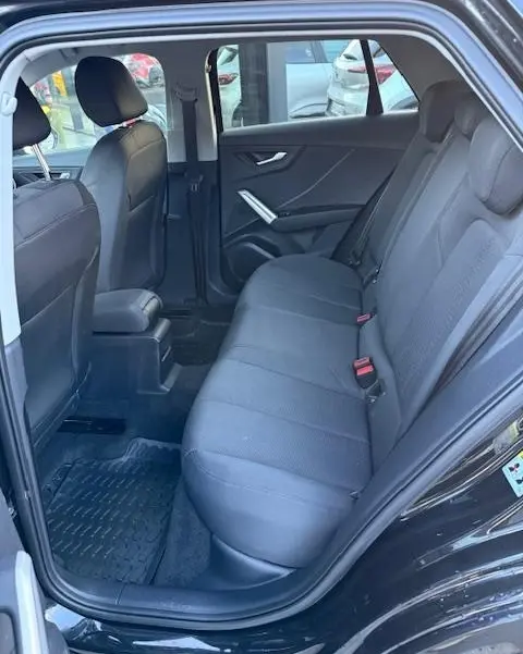 Vue intérieure côté droit sur la banquette arrière noire de l'Audi Q2 35 TFSI S Line 2023 avec portes ouvertes.