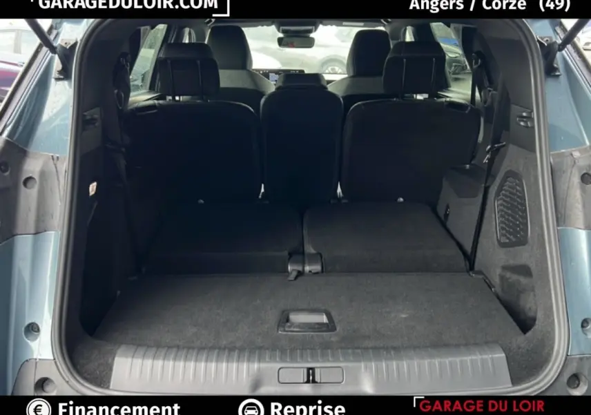 Vue arrière du coffre ouvert du Peugeot 5008 bleu 2024 avec sièges arrière rabattus et espace de chargement plat.