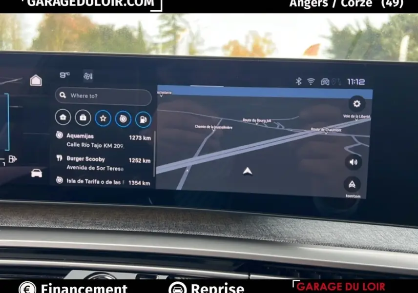 Vue rapprochée de l’écran tactile du tableau de bord du Peugeot 5008 bleu 2024, affichant le GPS et les options de navigation.