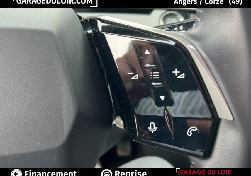 Gros plan sur les commandes au volant noir brillant du Peugeot 5008 bleu 1.2 Hybrid 136 Allure, côté gauche.