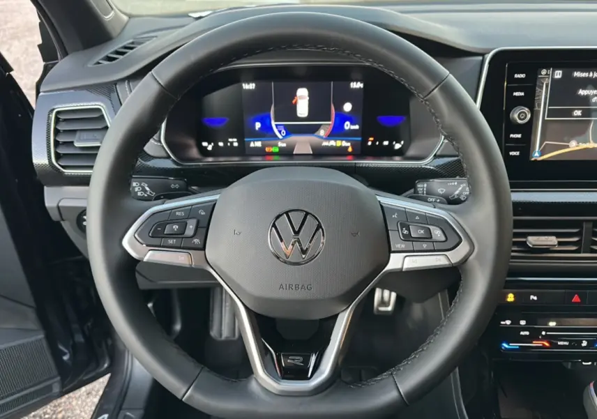 Vue centrée sur le volant cuir multifonctions du Volkswagen T-Cross gris cendré avec tableau de bord digital et écran tactile.