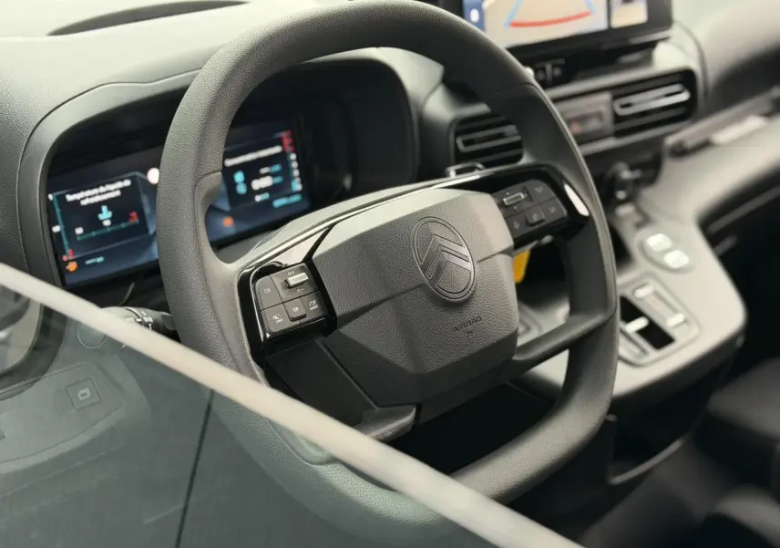 Vue intérieure centrée sur le volant multifonctions noir du Citroën Berlingo avec tableau de bord numérique et écran tactile.