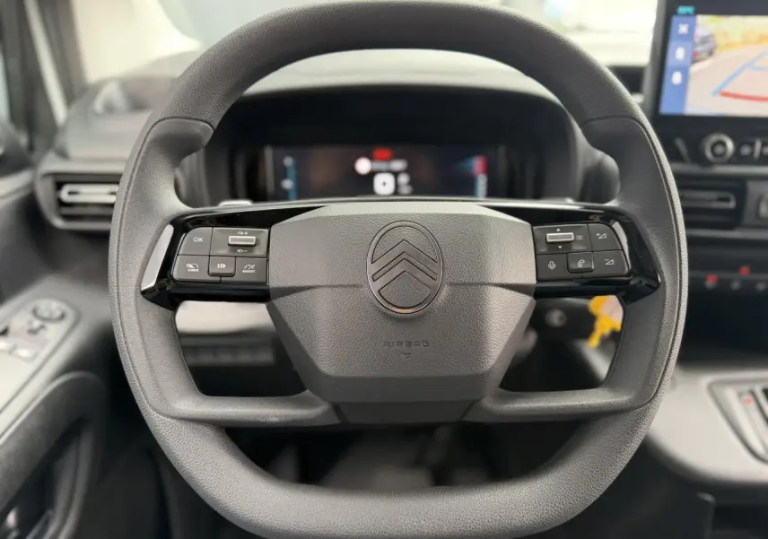 Vue rapprochée du volant multifonctions noir du Citroën Berlingo 2026, avec tableau de bord numérique et écran tactile visible.