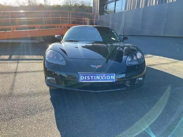 Vue frontale d'une Chevrolet Corvette C6 Targa noire de 2005, avec plaque Distinxion et phares Xénon visibles.