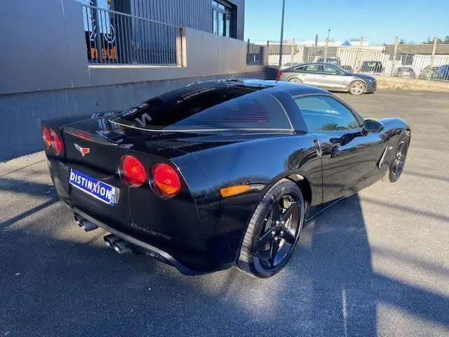 Vue 3/4 arrière droite d'une Chevrolet Corvette C6 Targa noire de 2005 avec jantes noires et feux ronds rouges.
