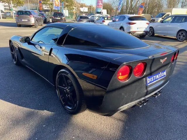 Chevrolet Corvette C6 Targa noire vue 3/4 arrière droit, feux ronds rouges et jantes noires brillantes visibles.