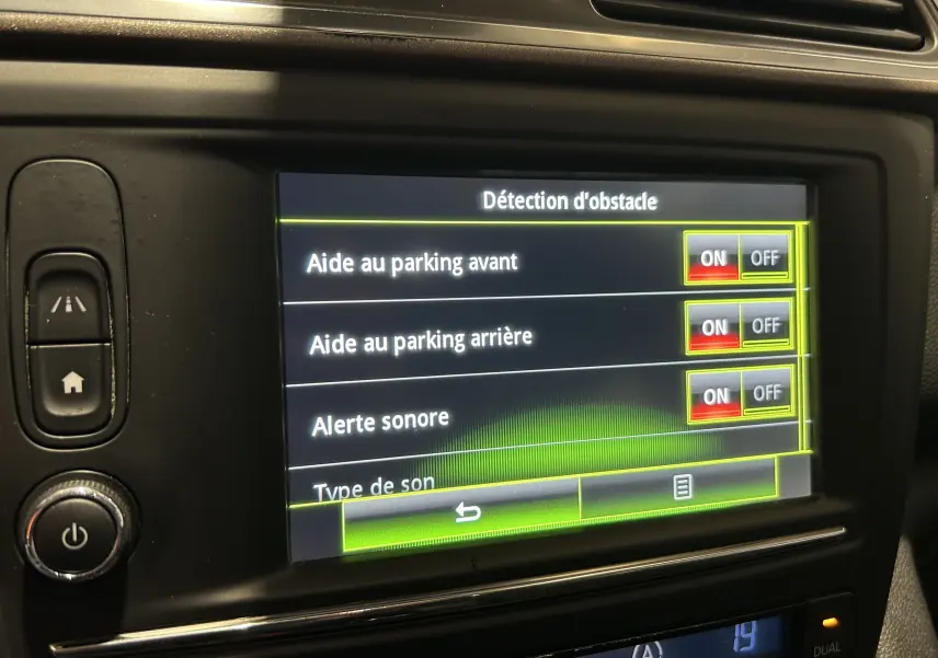 Écran central du tableau de bord du Renault Kadjar gris 2015 montrant les réglages d'aide au parking activés.
