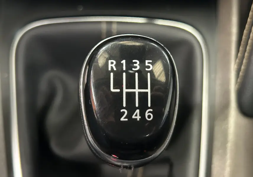 Gros plan sur le levier de vitesses manuel noir du Renault Kadjar gris diesel de 2015, affichant les six rapports et la marche arrière.