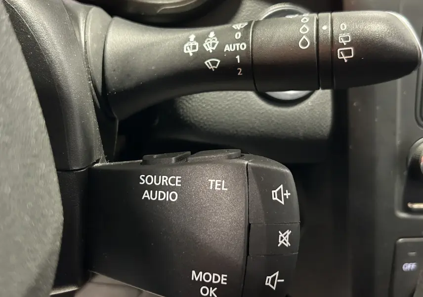 Gros plan sur les commandes audio et essuie-glace noires du tableau de bord du Renault Kadjar gris 2015.