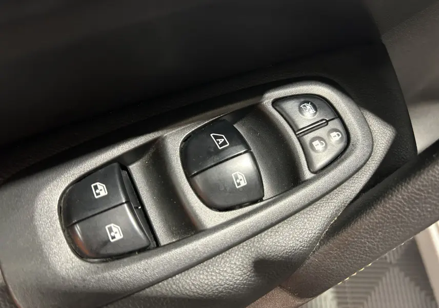 Gros plan sur les commandes de lève-vitres et verrouillage des portes côté conducteur d'un Renault Kadjar gris 2015.