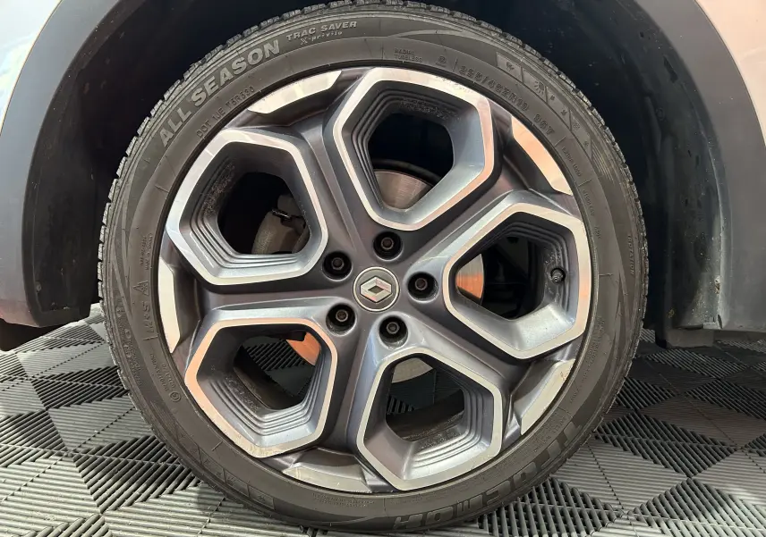 Gros plan sur la roue avant gauche d'un Renault Kadjar gris 2015, mettant en valeur le pneu et l'aile du véhicule.