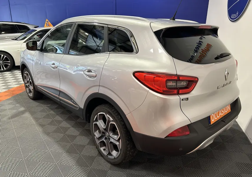 Vue 3/4 arrière droite d'un Renault Kadjar gris 2015 avec jantes alliage et vitres teintées en showroom.
