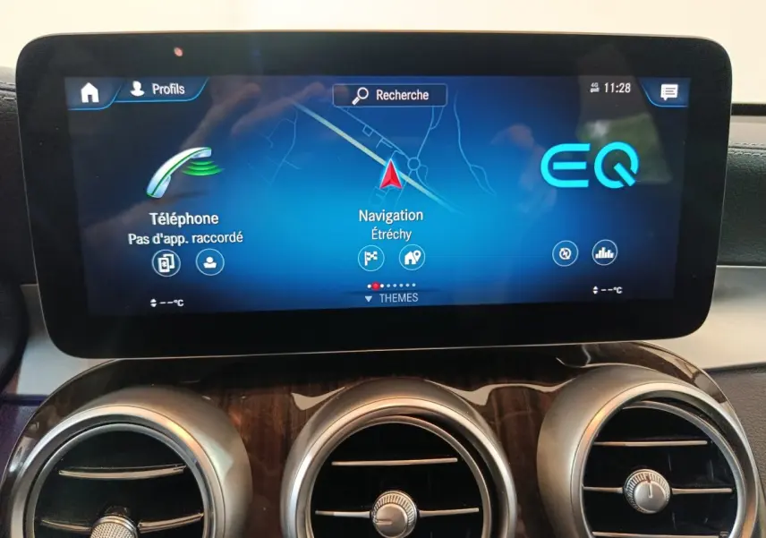 Écran tactile central avec navigation et téléphone, tableau de bord bois et aérateurs ronds du Mercedes GLC 300 e noir.