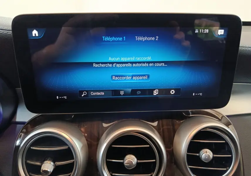Écran tactile central bleu affichant la connexion Bluetooth, avec trois aérateurs ronds chromés sur tableau de bord noir du Mercedes GLC 300 e.