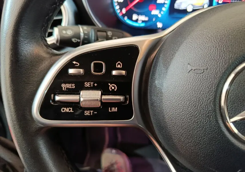 Gros plan sur le volant cuir noir du Mercedes GLC 300 e, avec commandes multifonctions et tableau de bord numérique.