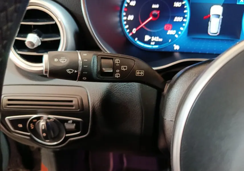 Gros plan sur la commande d’essuie-glace et le tableau de bord numérique bleu d’un Mercedes GLC 300 e noir de 2020.