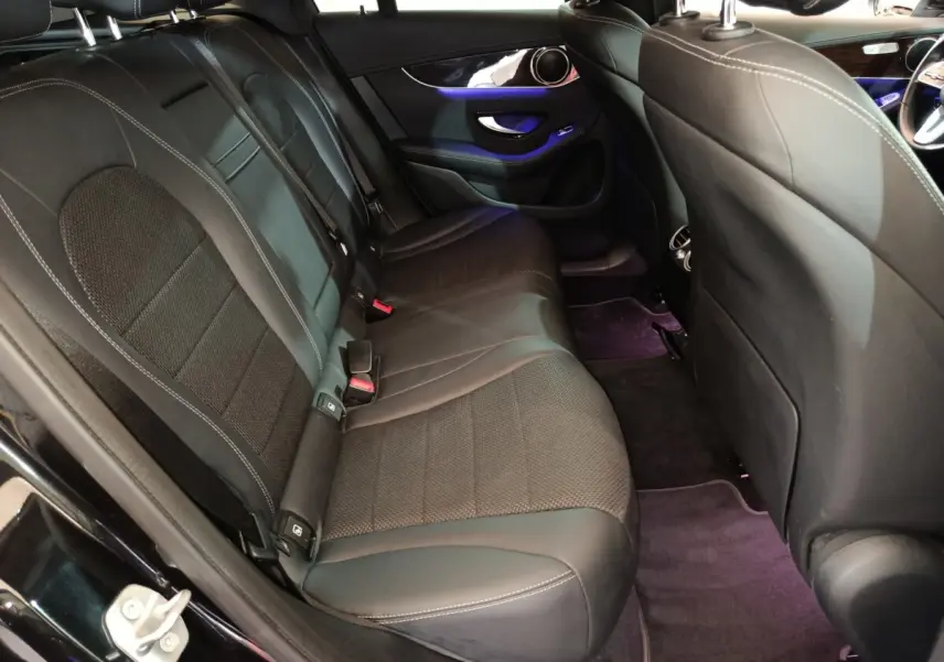 Vue intérieure arrière côté gauche du Mercedes GLC 300 e noir, sièges en cuir noir avec éclairage d'ambiance violet.