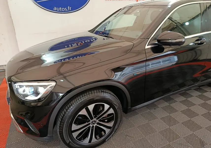 Vue 3/4 avant côté gauche d'un Mercedes GLC 300 e Business Line noir brillant avec jantes alliage distinctives.