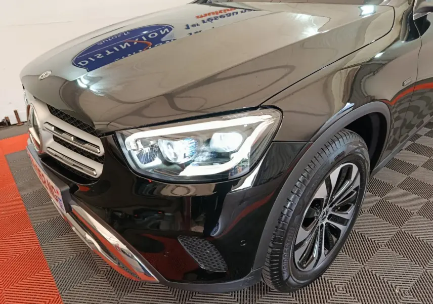 Vue 3/4 avant droit d'un Mercedes GLC 300 e Business Line noir avec phares LED allumés et jante alliage distinctive.