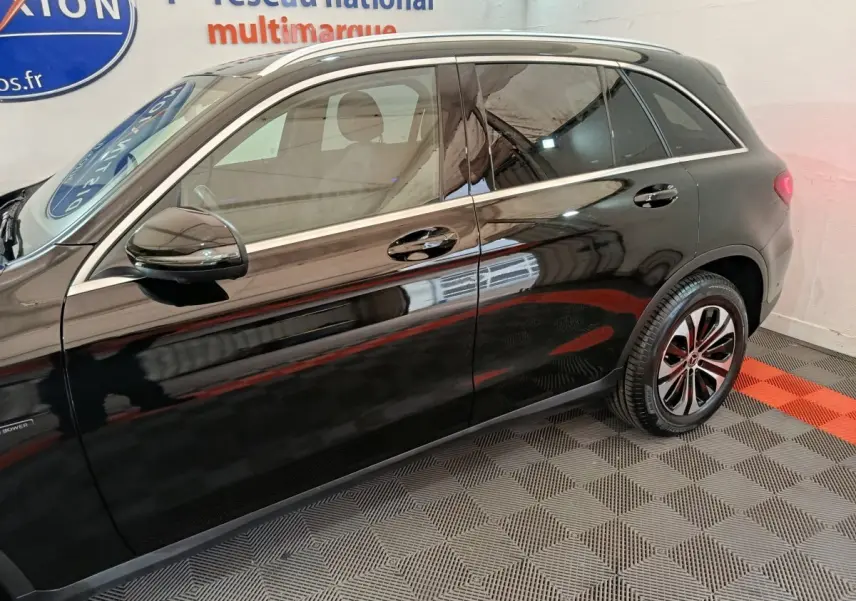 Vue latérale côté gauche d'un Mercedes GLC 300 e Business Line noir stationné en intérieur sur sol damier.
